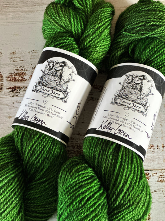 Two skeins of green yarn with labels on a wooden surface
