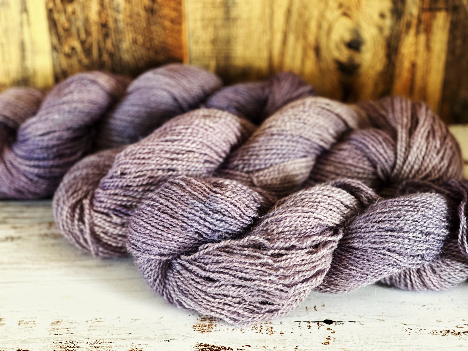 Bundles of purple yarn on a wooden surface