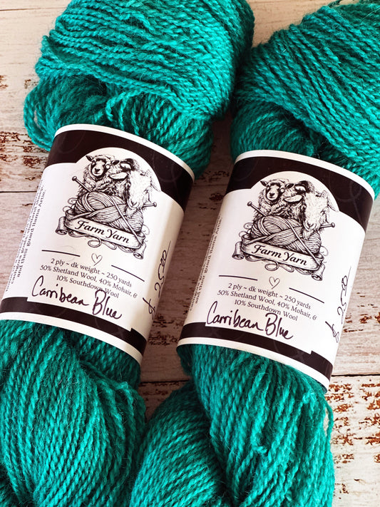 Two skeins of teal yarn with labels on a wooden surface