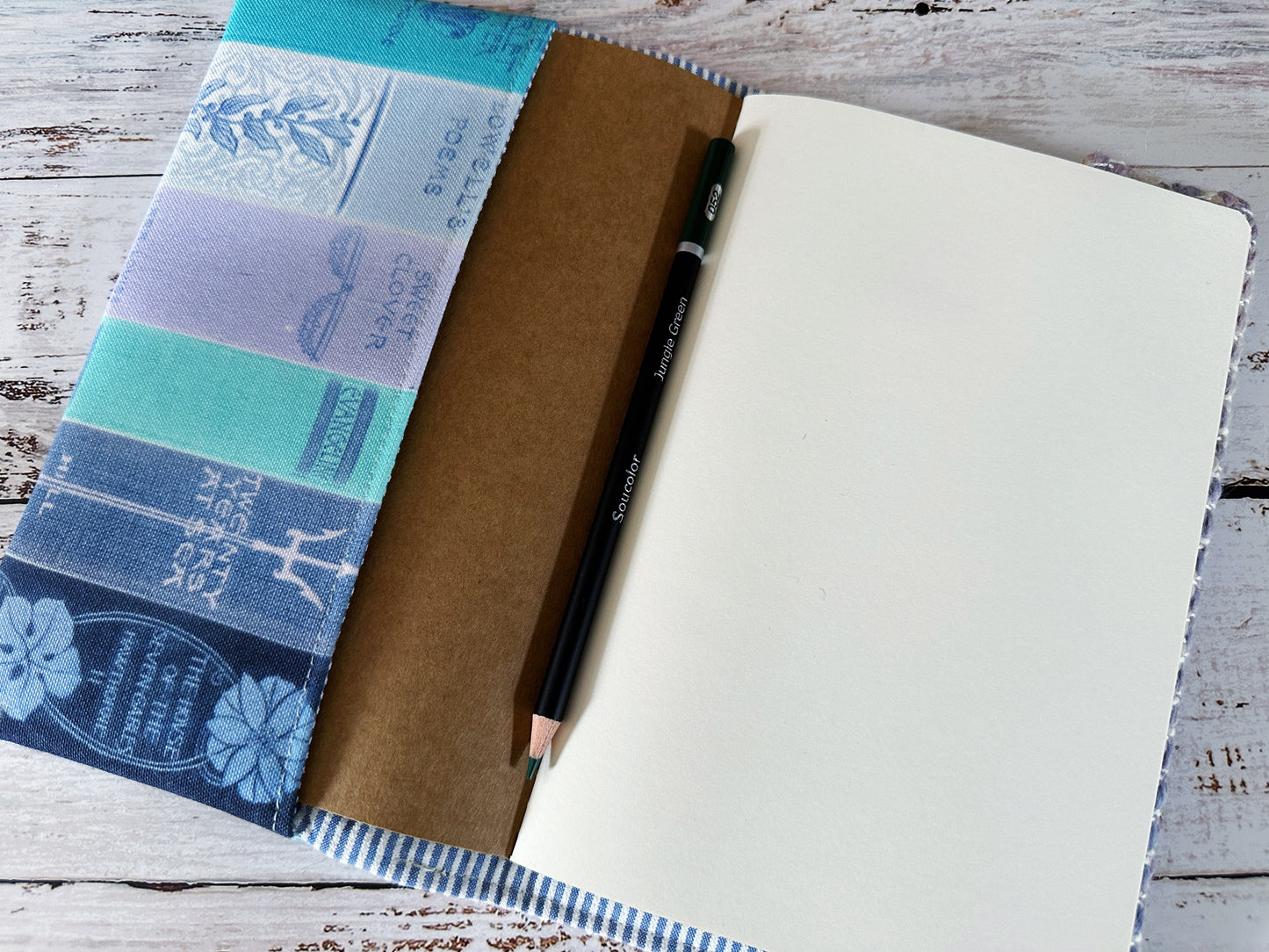 Notebook with a pencil on top, wrapped in decorative paper on a wooden surface