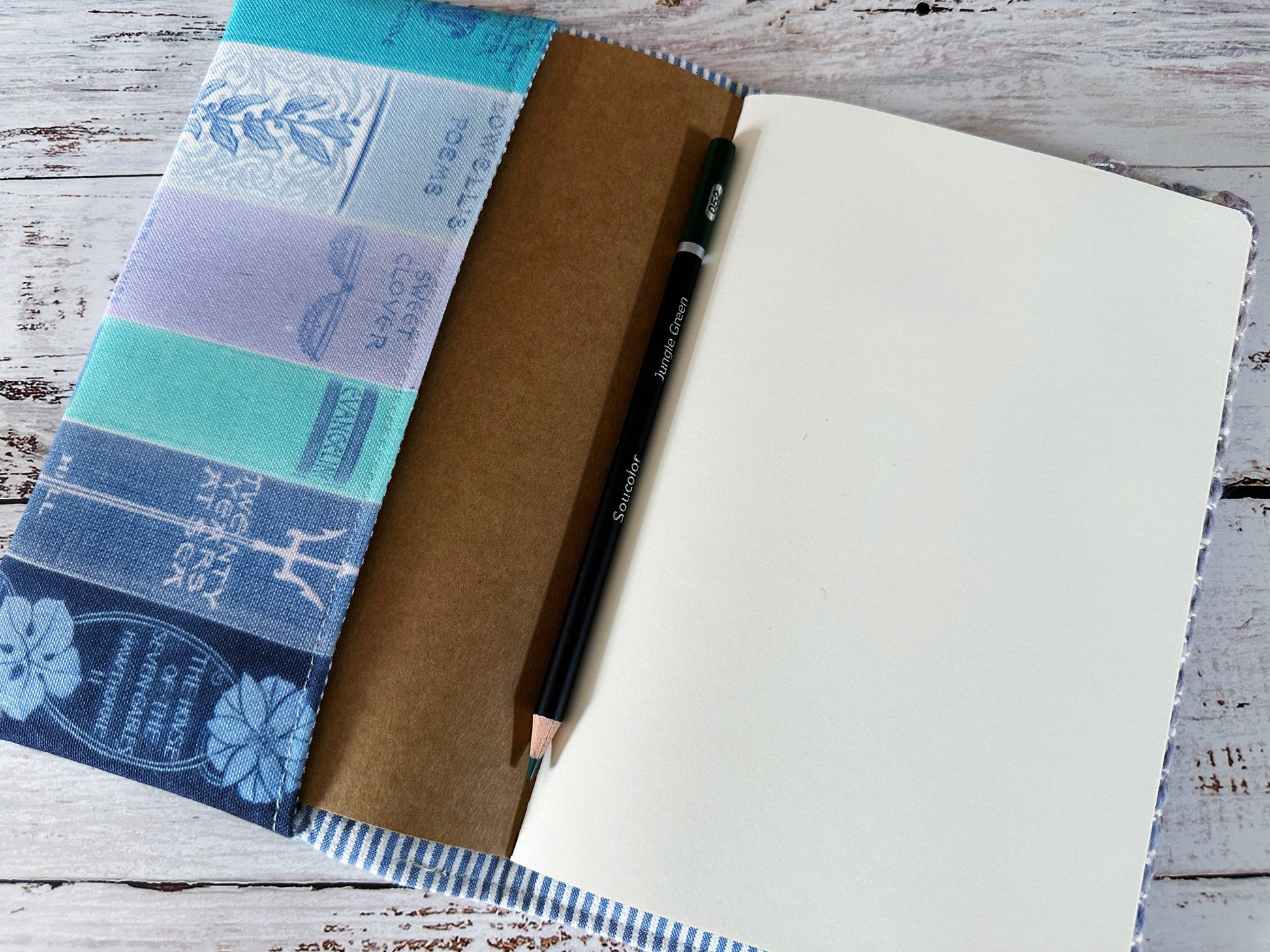 Notebook with a pencil on top, wrapped in decorative paper on a wooden surface
