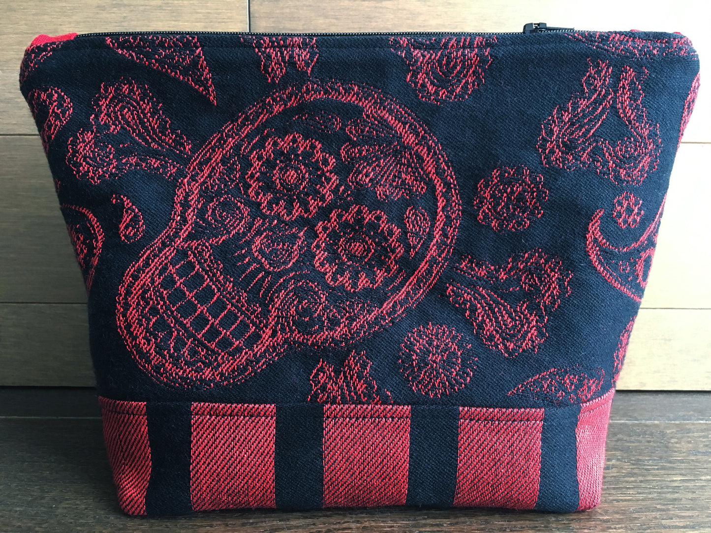 Image of a large handmade pirate themed essential oil organizer. It features a large skull and crossbones embroidery on faux alligator leather, bold red and black skull woven textile. The inside is made from blood red linen and skelewags fabric from Alexander Henry. It  has 10 built in pockets and 3 inserts with 3 pockets each.  