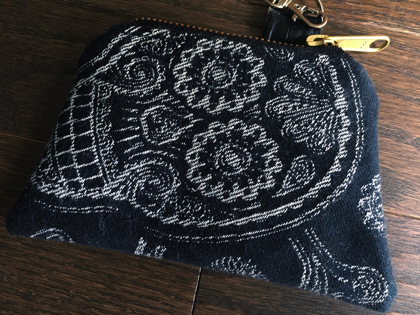 Image of a handmade and pirate themed coin purse featuring a pirate mermaid crest embroidered on faux black alligator leather and backed with beautiful black and white skull and crossbones woven wrap scrap fabric. 
